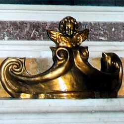 Il Cartiglio in creta misura 36x12 sormontato da un Angioletto a mezzo busto con le ali spiegate. Rifinitura in bronzo dorato. Il Cartiglio è posto sulla tomba del Sommo Pittore-Scultore viterbese Pietro Vanni dell'800